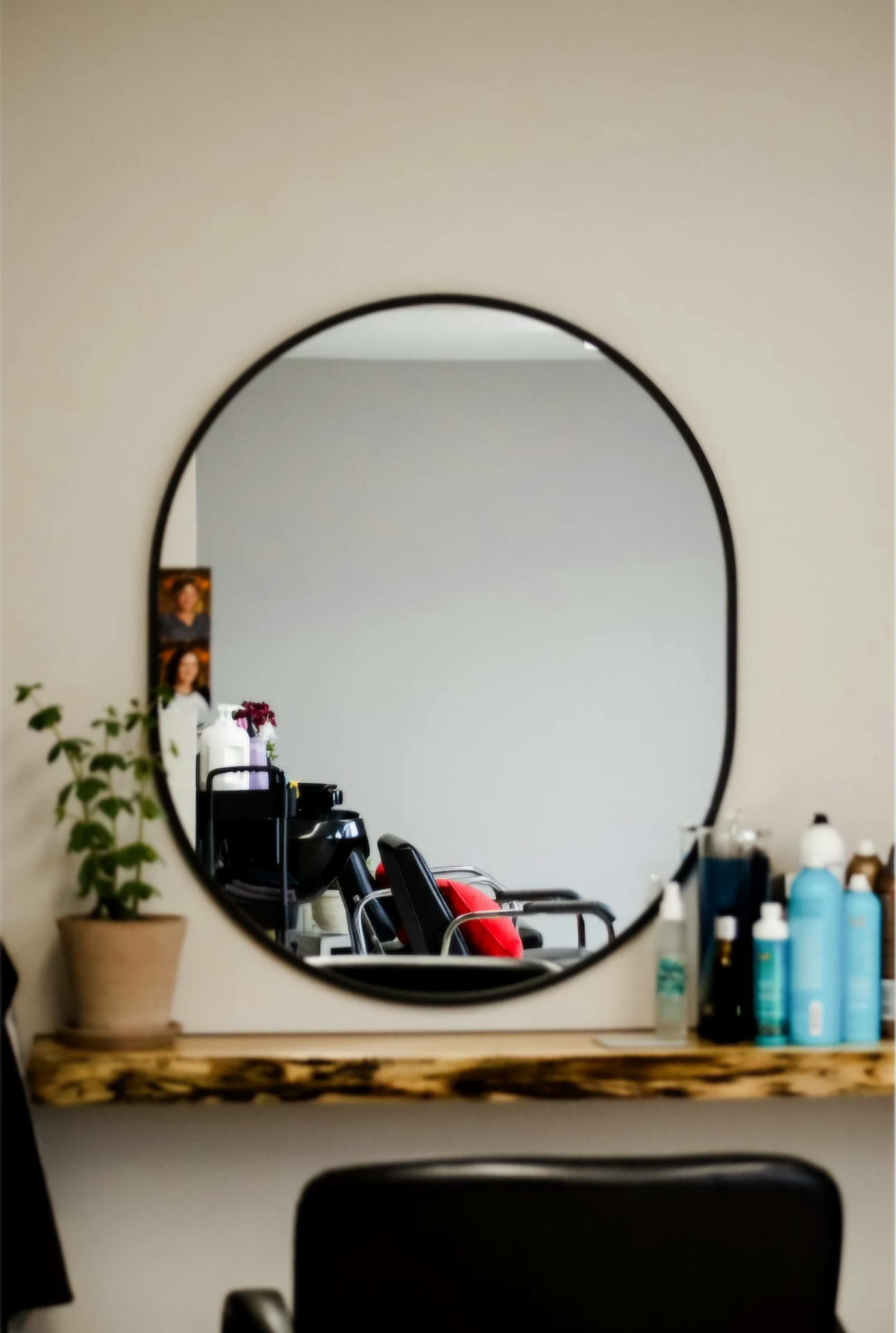 Sculptural black-framed mirror above a live-edge wood shelf
