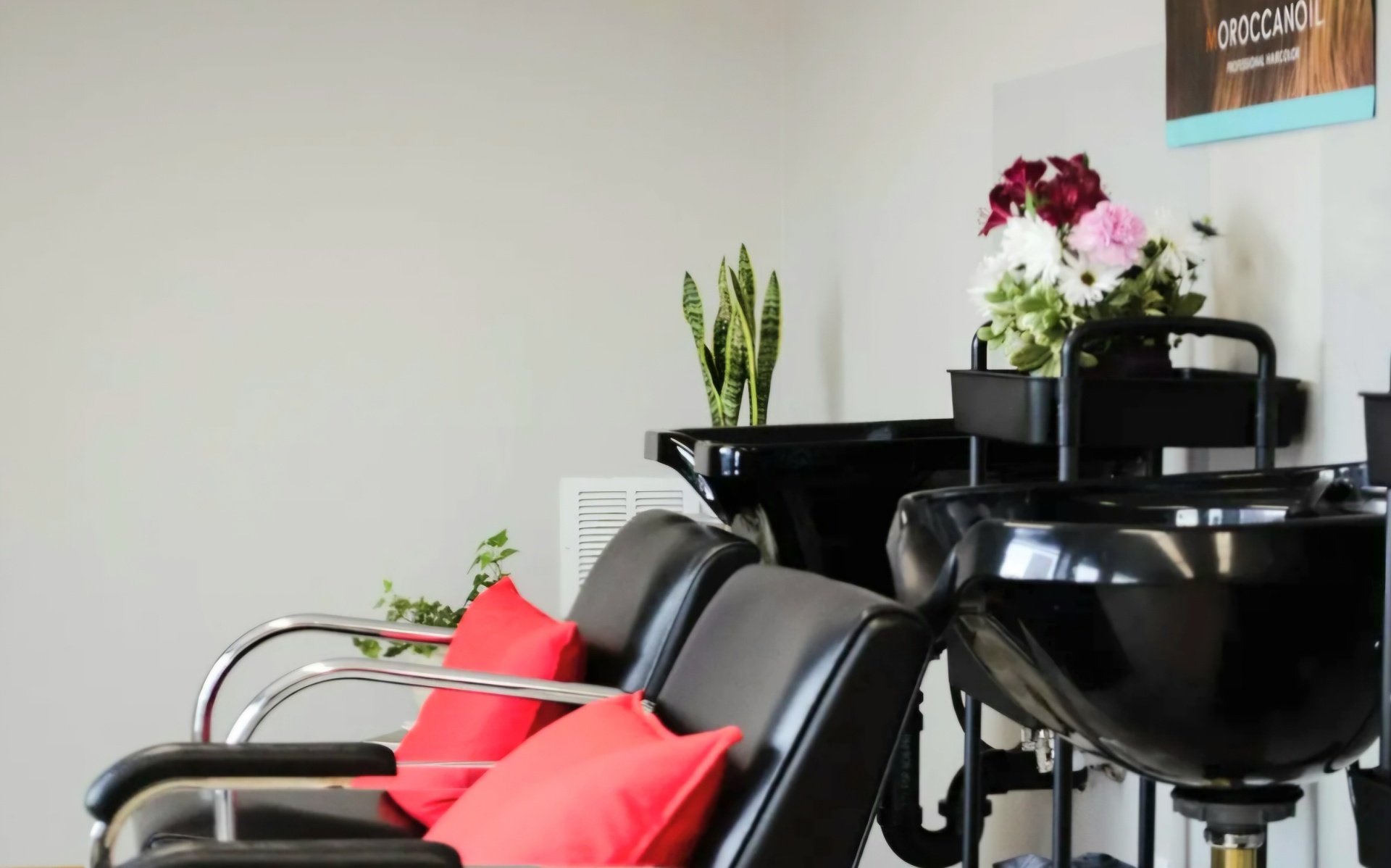Salon shampoo bowls with red accent pillows and fresh flowers